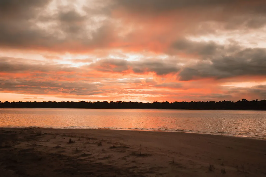 Lake with Sunset over the water and trees across 